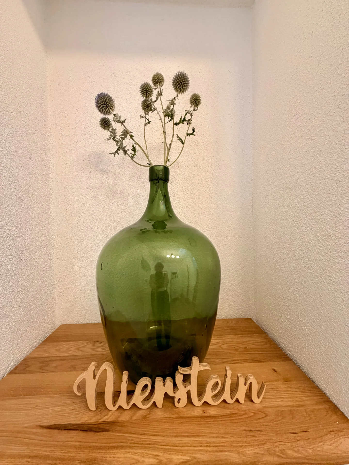 Grüne Glasvase mit Trockenblumen und dekorativem Nierstein-Schriftzug im Markt Quartier.
